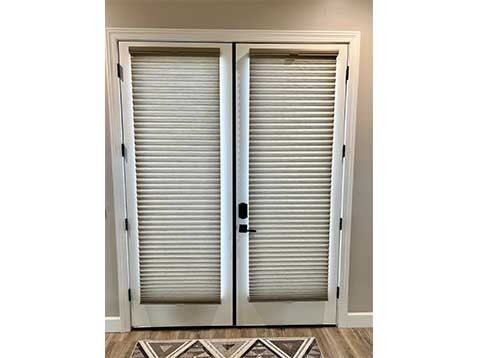 A double glass door covered by honeycomb shades